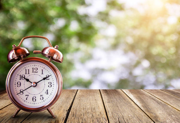reloj despertador retro sobre una mesa de madera con fondo borroso. - daylight savings fotografías e imágenes de stock