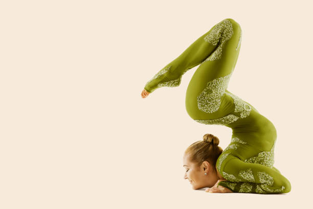 contorsionista flexible circus performer, acrobat dancer en traje verde, yoga mujer gimnasta beige fondo - acróbata circo fotografías e imágenes de stock