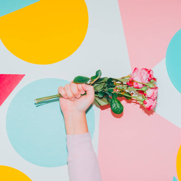 istock Hand holds spring flower bouquet on colorful background. Modern creative Valentines or woman's day concept. Pop art style 1299730662