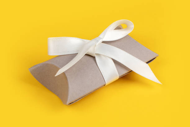 istock Gray gift box with silver ribbon on yellow background 1299731892
