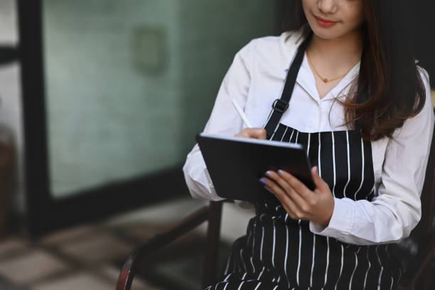 istock Young Asian woman barista using digital tablet receive orders from customers. 1299732046