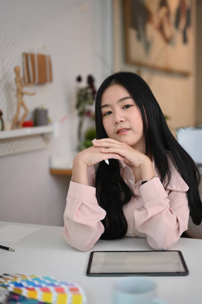 istock Attractive young woman designer sitting at her workspace with digital tablet and looking at camera. 1299732076