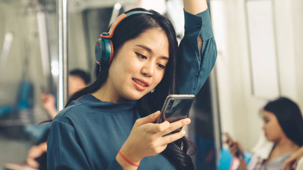 公共の電車で携帯電話を使用して若い女性 - リスニング 電車 ストックフォトと画像