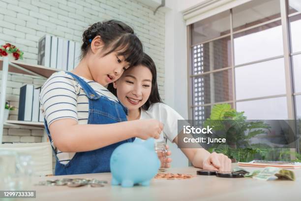 Mother Is Teaching Daugther On Financial Saving And Planing Using Saving Jar And Piggy Bank With Real Moner For Money And Wealth Education Concept Stock Photo - Download Image Now
