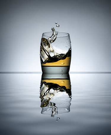 Ice dropping into a glass of Scotch.