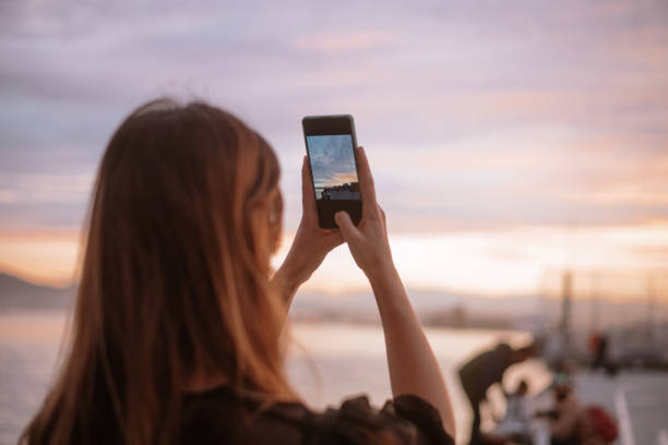 istock Young woman taking a picture of a sunset 1299734430