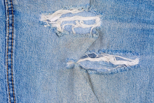 istock Holes on blue jeans with frayed threads close-up 1299735284