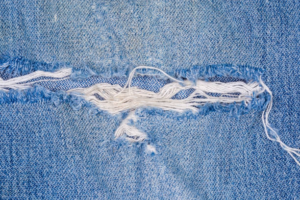 istock Hole with frayed threads in old torn jeans close-up 1299735728