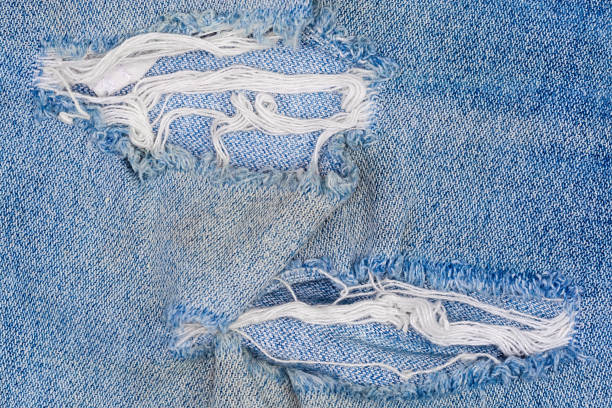 istock Hole on denim jeans with frayed threads close-up 1299735776