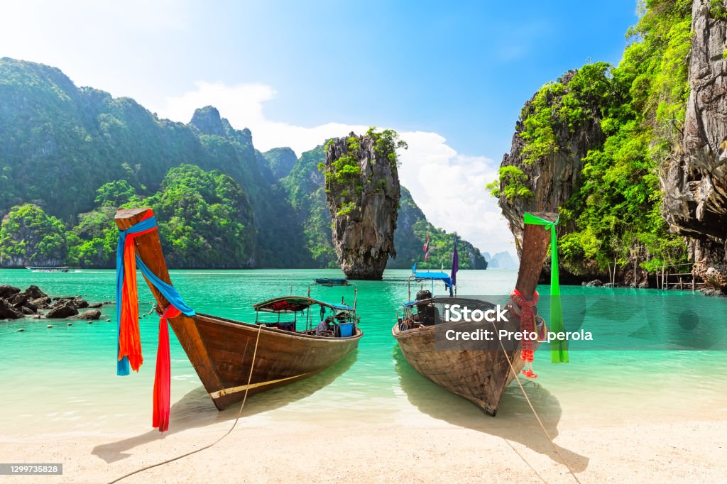 Travel photo of James Bond island with thai traditional wooden longtail boat and beautiful sand beach in Phang Nga bay, Thailand. Famous James Bond island near Phuket in Thailand. Travel photo of James Bond island with thai traditional wooden longtail boat and beautiful sand beach in Phang Nga bay, Thailand. Thailand Stock Photo