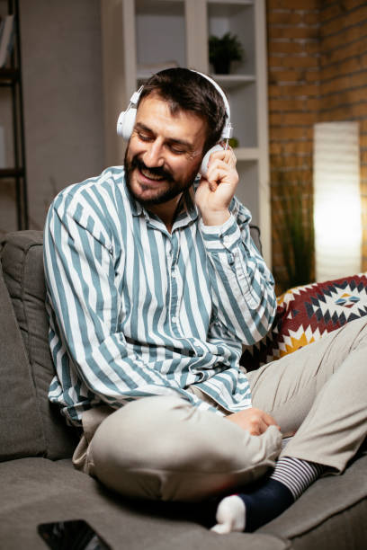istock Young man with headphones resting on sofa. 1299737391