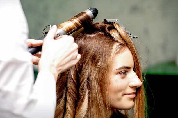 istock Hairdresser makes curls with curling iron 1299738094