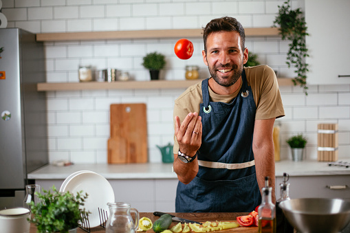 Portrait of handsome man in kitchen. Young man preparing salad.