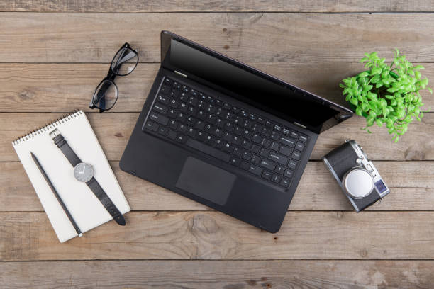 istock Workplace from above - laptop, notepad, glasses and camera on the wooden desk 1299740025