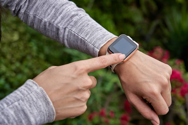 Young woman tries out a generic but modern touch screen smart-watch on his wrist.