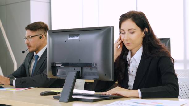 istock Business people wearing headset working in office 1299745489