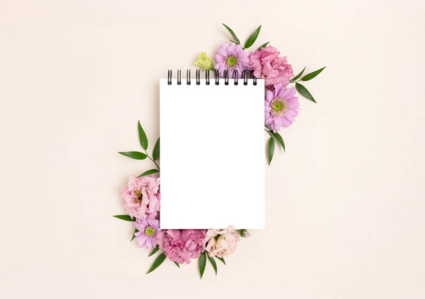 istock Frame made of eustoma flower and blank notepad mockup on a beige background. 1299745767