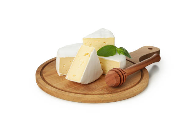 istock Cutting board with camembert, basil and dipper isolated on white background 1299745780