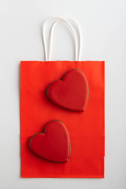 istock Red paper bag and gingerbread hearts on white background. Vertical frame. Mothers day. Valentines day 1299746434