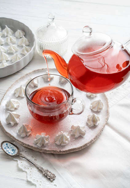 tè rosso all'ora del tè con teiera che fa le fusa sulla tazza con bacio di meringa - english breakfast tea foto e immagini stock