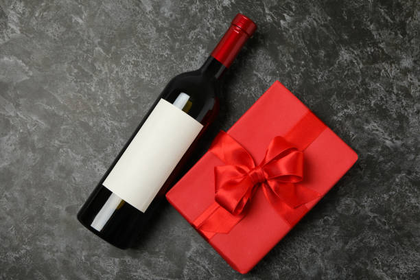 istock Bottle of wine and gift box on black smokey background 1299748012