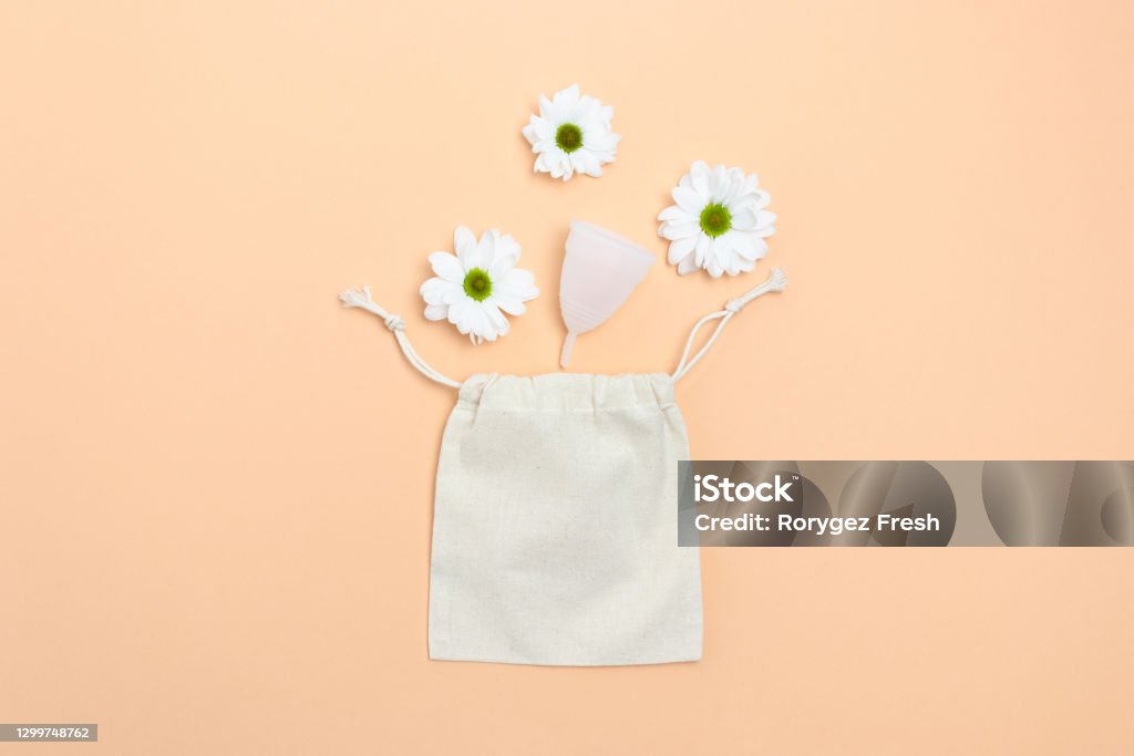 White chamomile flowers, menstural cup and canvas sack on yellow background. Plastic free concept. Zero Waste Stock Photo