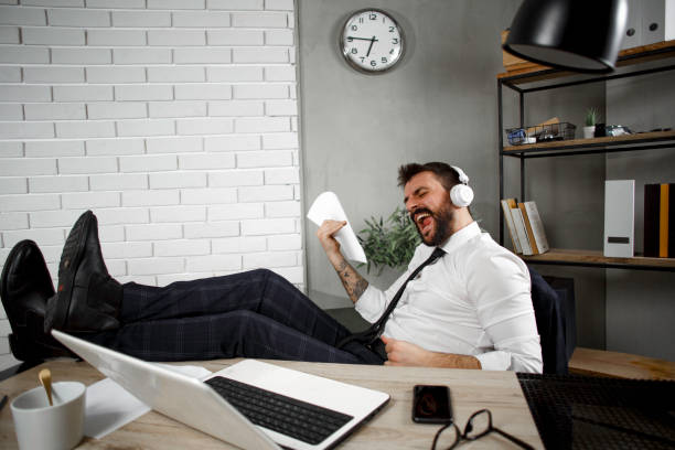 istock Young businessman with headphones singing at work. 1299749265