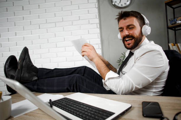 istock Young businessman with headphones singing at work. 1299749425