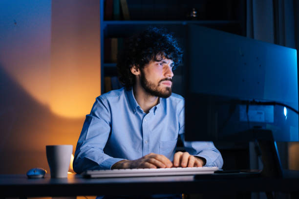 istock Exhausted freelancer watching on monitor, working typing on keyboard and drinking hot coffee. 1299750294