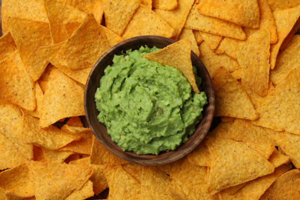 istock Bowl of guacamole on chips background, top view 1299750384
