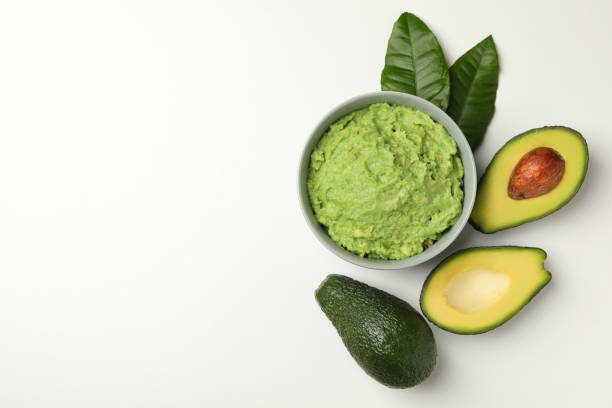 istock Bowl of guacamole and avocado on white background, space for text 1299750774