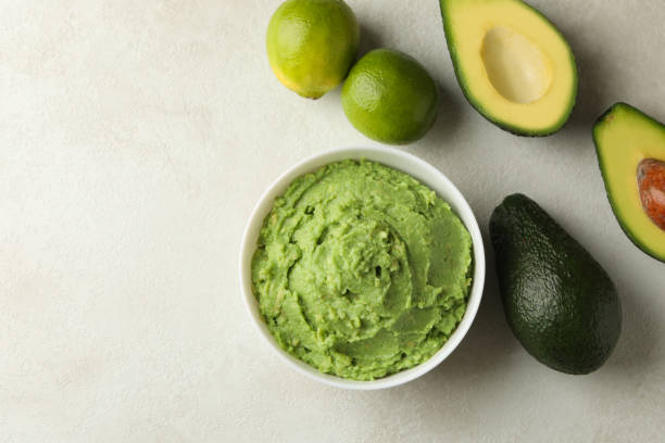 istock Bowl of guacamole, avocado and lime on white textured background, space for text 1299750882