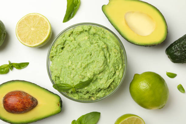 istock Bowl of guacamole, avocado, lime and basil on white background, top view 1299751031