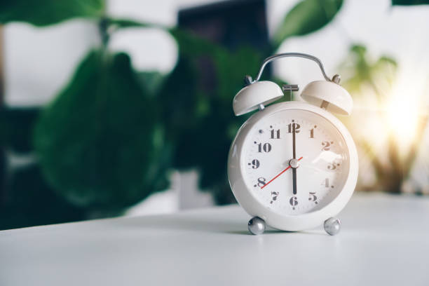 istock Selective focus of alarm clock show 6 o'clock or 6 a.m. on table with nature bokeh background. Time in life concept. Early bird person. 1299753504