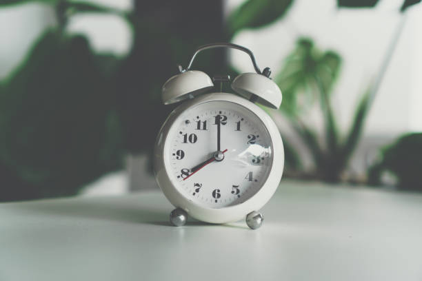 istock Selective focus of alarm clock show 8 o'clock or 8 a.m. on table with nature bokeh background. Time in life concept. 1299753545