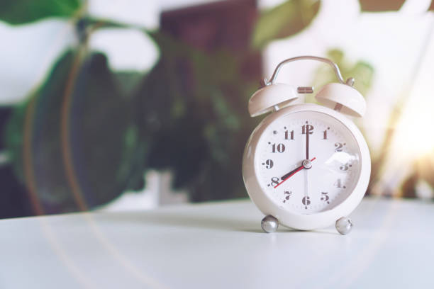 istock Selective focus of alarm clock show 8 o'clock or 8 a.m. on table with nature bokeh background. Time in life concept. 1299753551