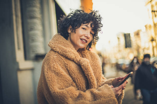 istock Female portrait on street with mobile.  Looking at camera. 1299753687