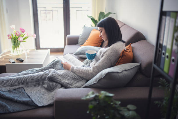 Young beautiful woman readinig a book at home