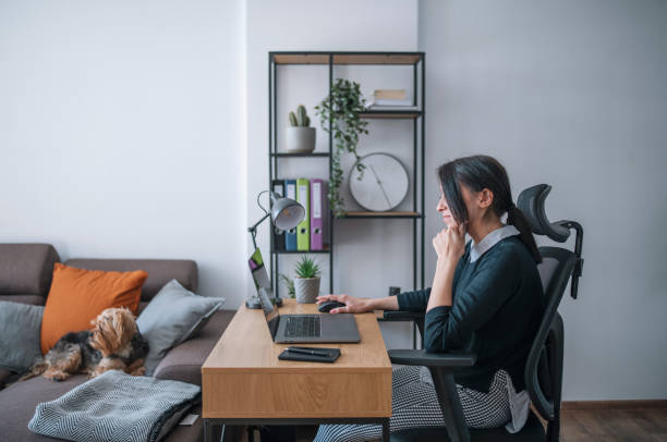 istock Young woman using a laptop at her home during the day 1299754267
