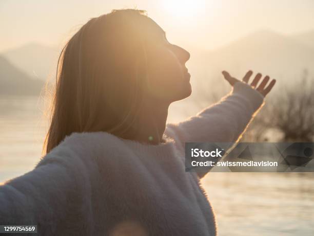 Woman Embraces Nature She Stands Arms Out By The Lake At Sunset Stock Photo - Download Image Now
