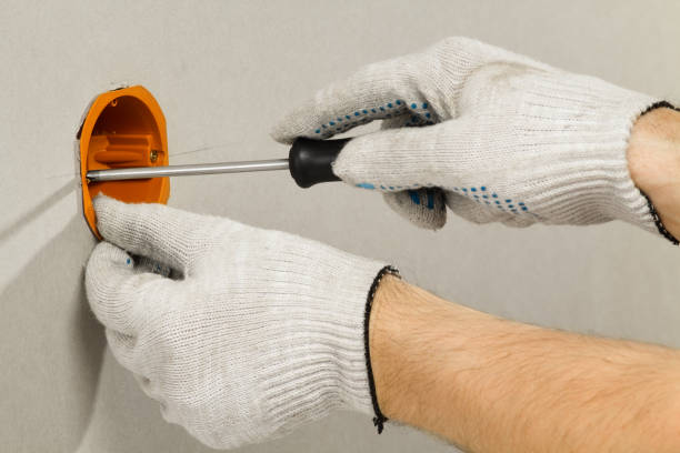 istock hands with a screwdriver fix the socket box to the drywall 1299754602