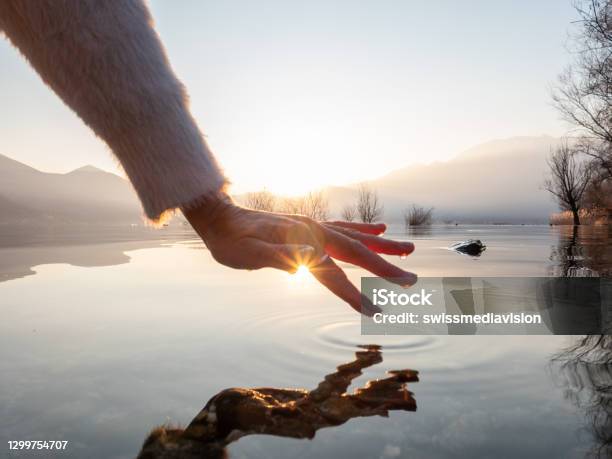 Detail Of Hand Touching Water Surface Of Lake At Sunset Stock Photo - Download Image Now