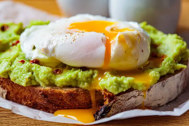 Avocado toast with poached egg on a wooden board. Breakfast concept.