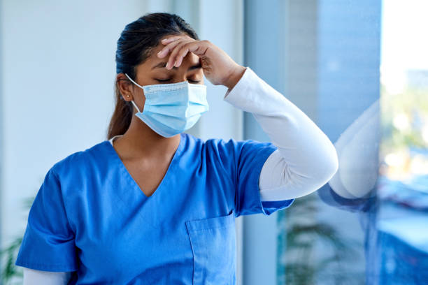 The risk of frontline worker stress is real Shot of a masked young doctor looking distressed mental burnout photos stock pictures, royalty-free photos & images