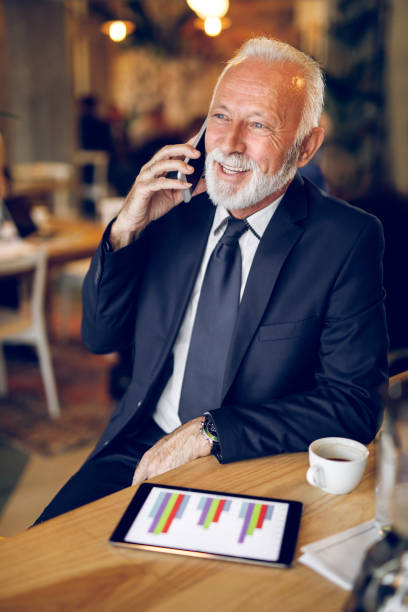istock Senior businessman using mobile phone and digital tablet in cafe 1299756917