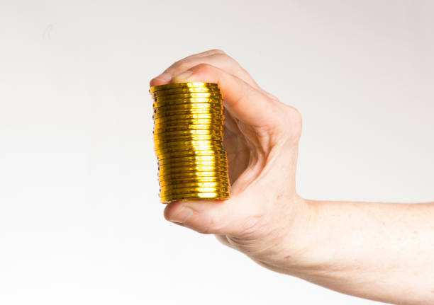 Cut out of one hand holding and displaying or showing a ten 10 rupees denomination coin in Indian currency money in gold and silver color isolated over white vertical colored transparent background with copy space