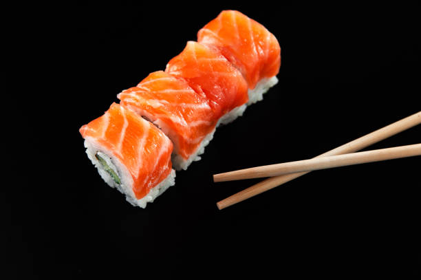 istock Sushi with red fish on a black background with bamboo sticks 1299757112