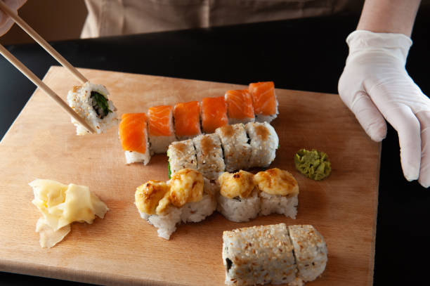 istock Woman eating delivered sushi from a container with japanese sticks 1299757294