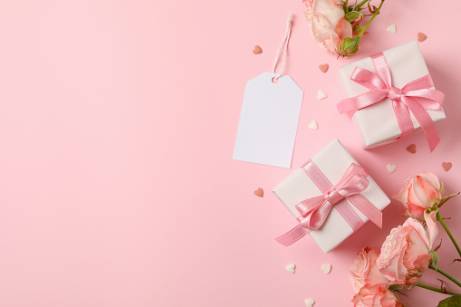 Concept of Valentine's day with roses and gift boxes on pink background