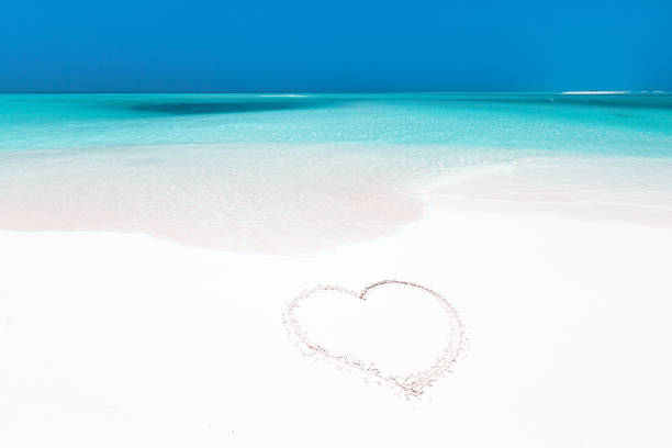 istock Heart symbol drawing on white sandy beach 1299759885